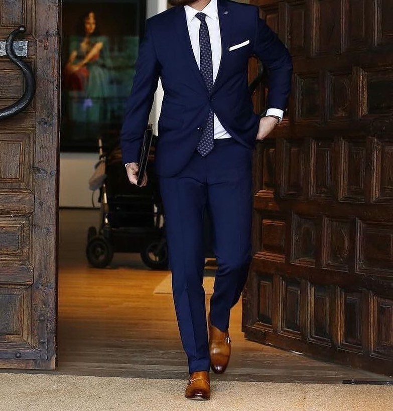 Man in navy blue suit and tie wearing brown leather dress shoes.