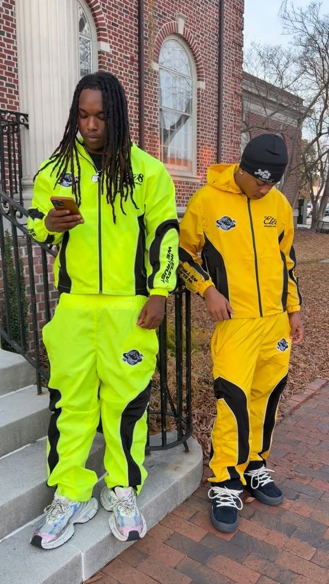Two men wearing neon yellow and yellow-green tracksuits standing on concrete steps.