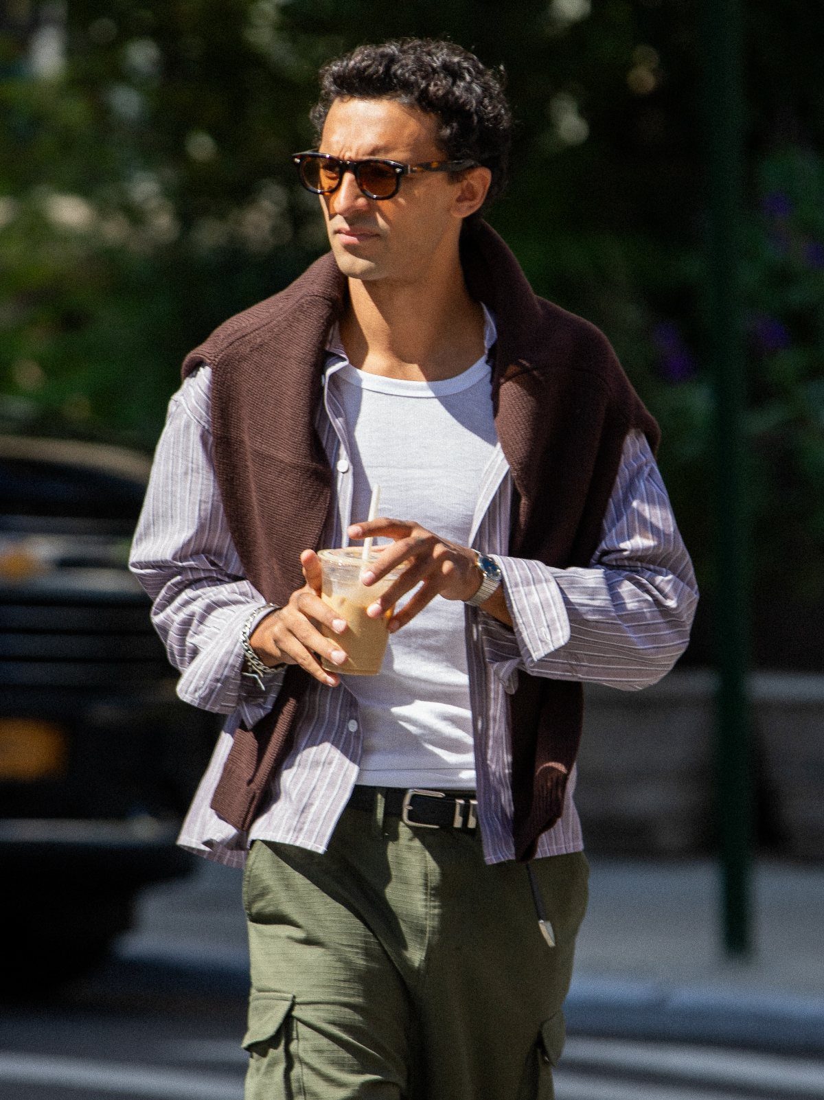 Man in a layered casual outfit with a brown vest and cargo pants.
