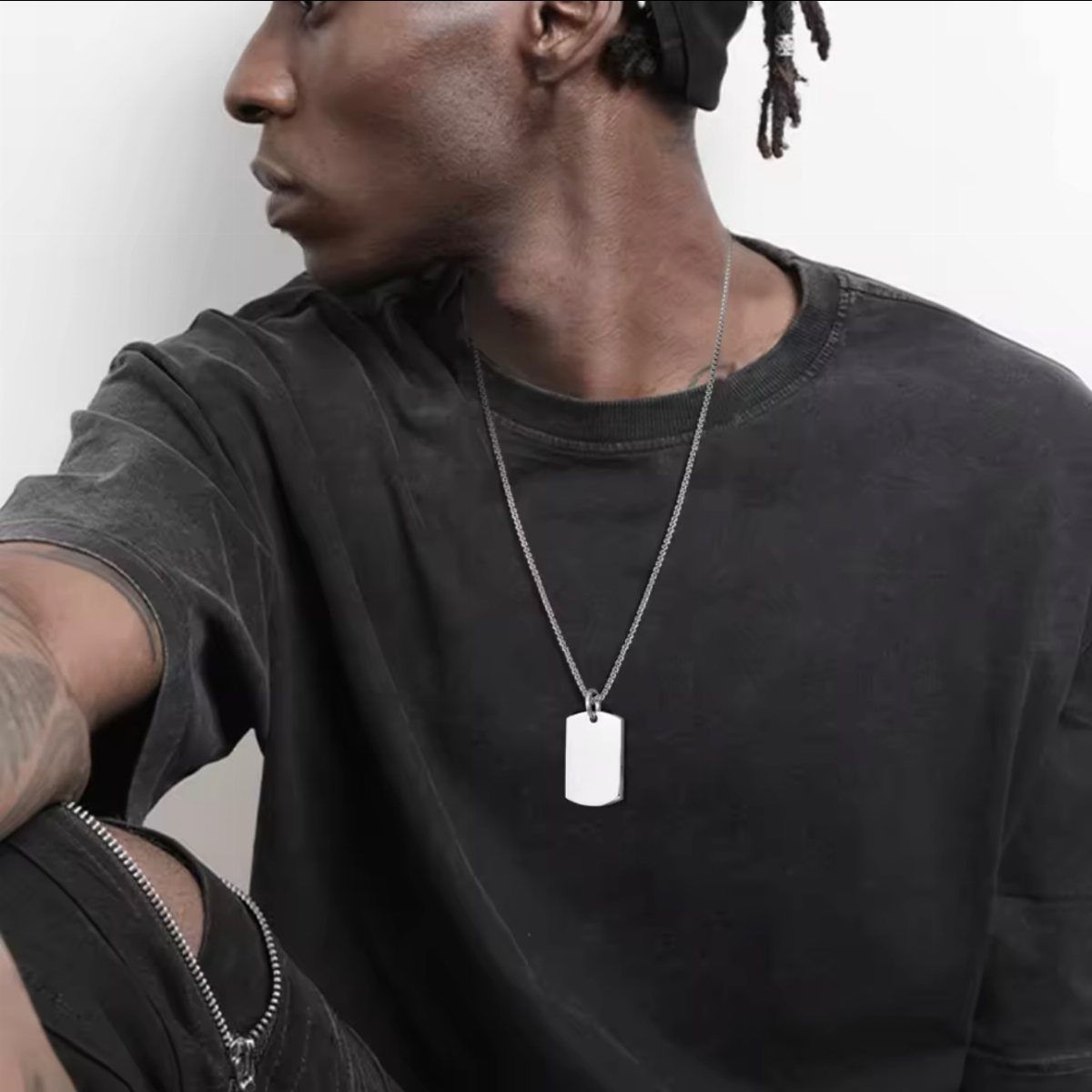Man in a dark grey t-shirt wearing a silver dog tag necklace.