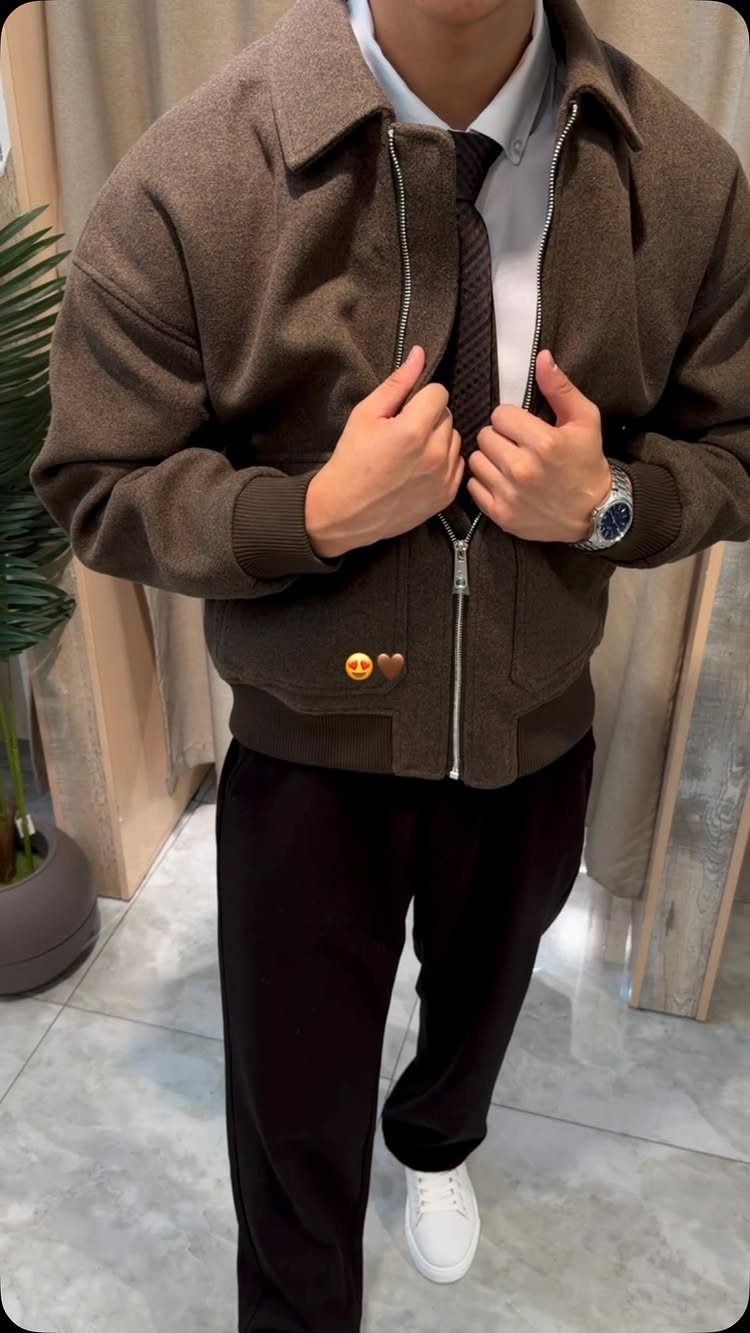 Person wearing a brown jacket, white shirt, dark tie, black pants, and white sneakers.