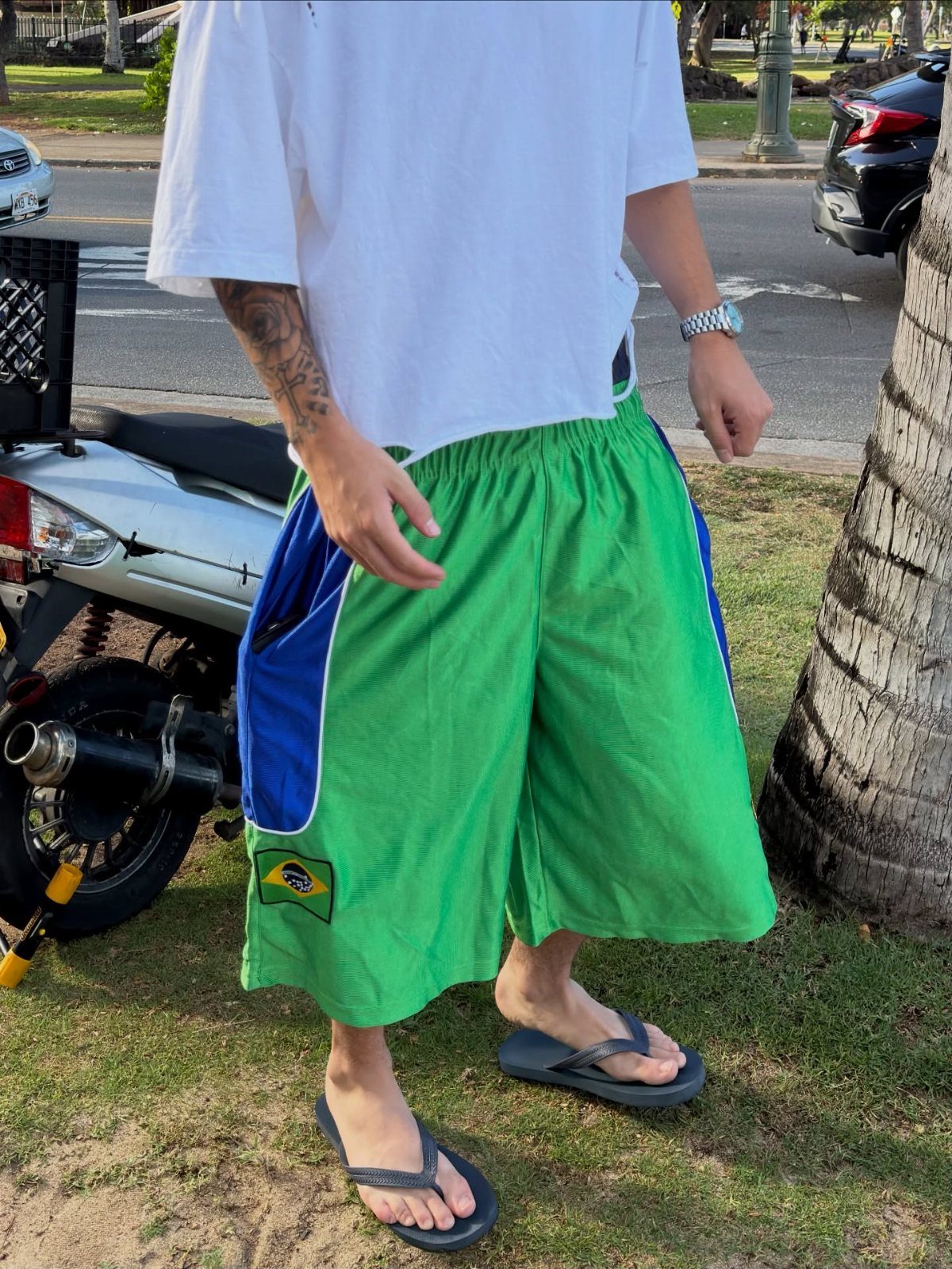 Person wearing bright green long shorts with blue panels and a white t-shirt.