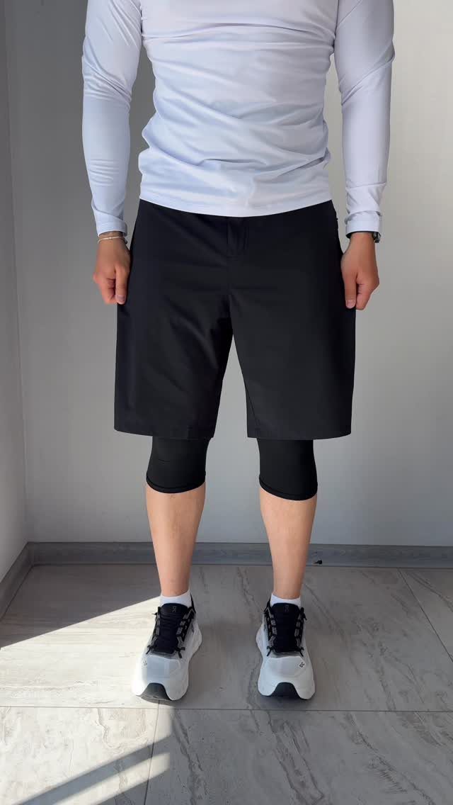 Person wearing a fitted white long-sleeve tee and black athletic long shorts.