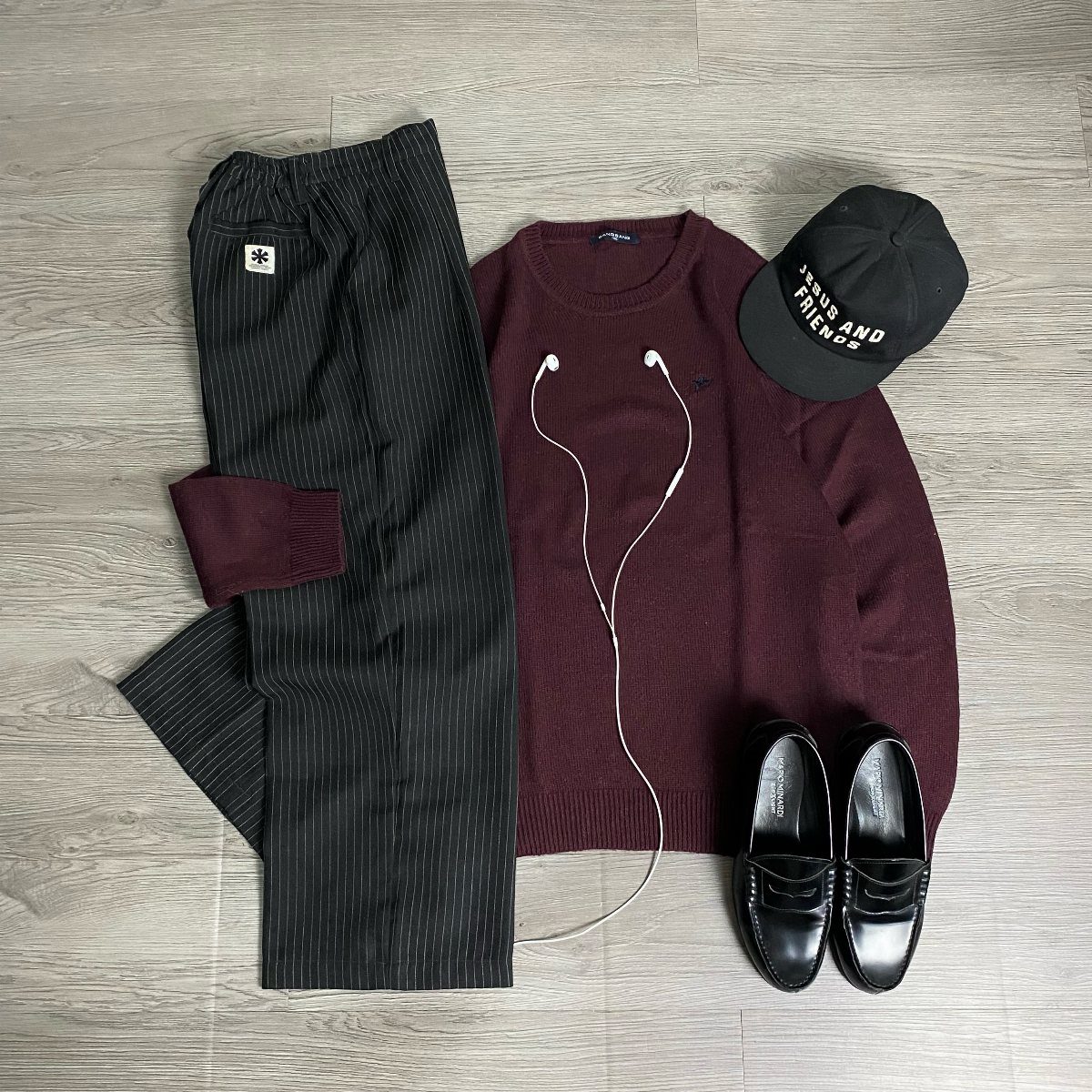 Burgundy crew-neck sweater and black pinstripe pants with black loafers and cap.