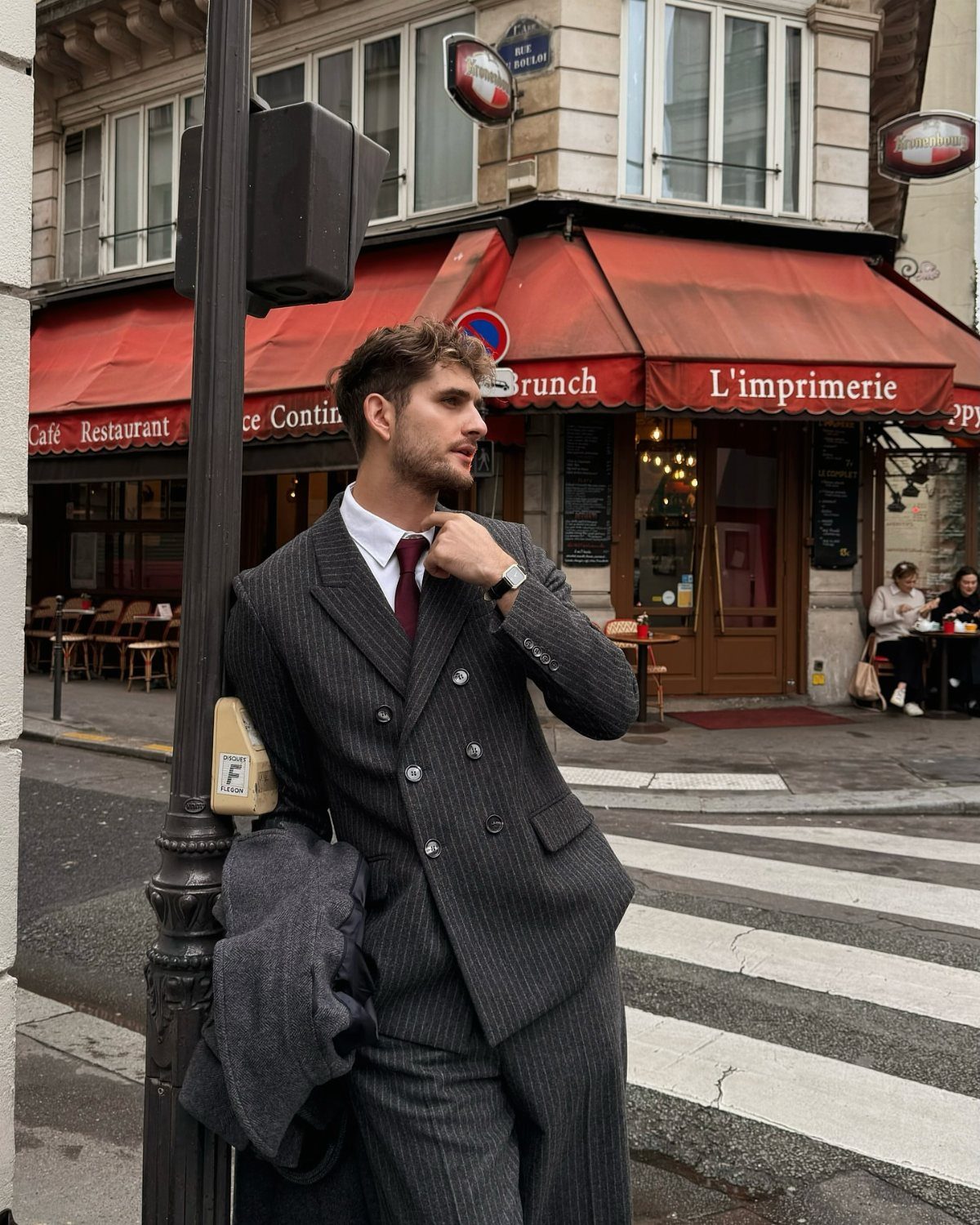 Man in charcoal pinstripe double-breasted suit and red tie on city street