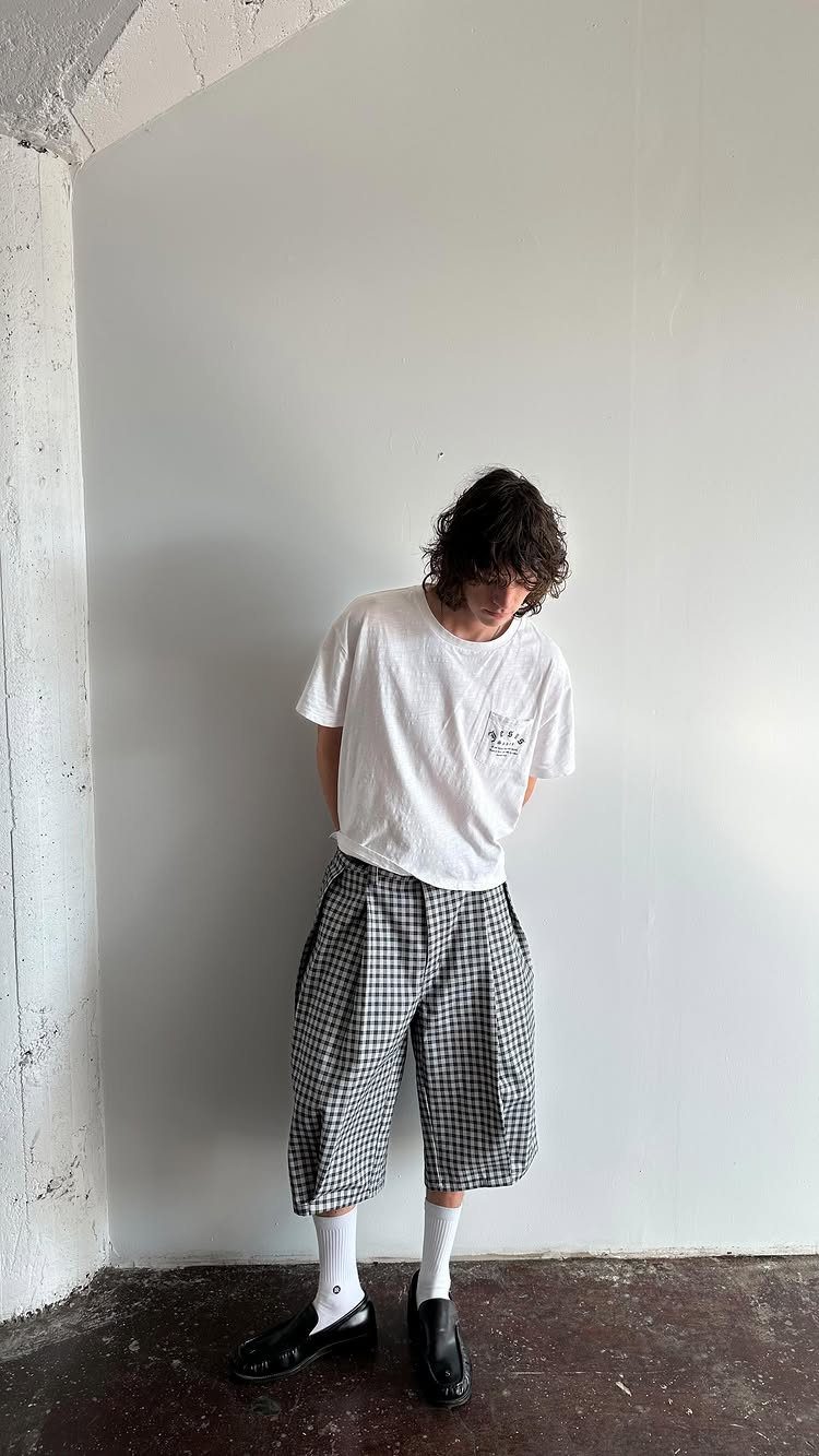 Person wearing a white t-shirt and oversized black and white plaid shorts.