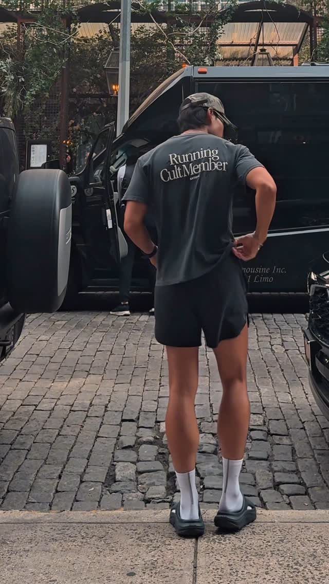 Person from behind wearing a grey t-shirt and black running shorts on cobblestones.