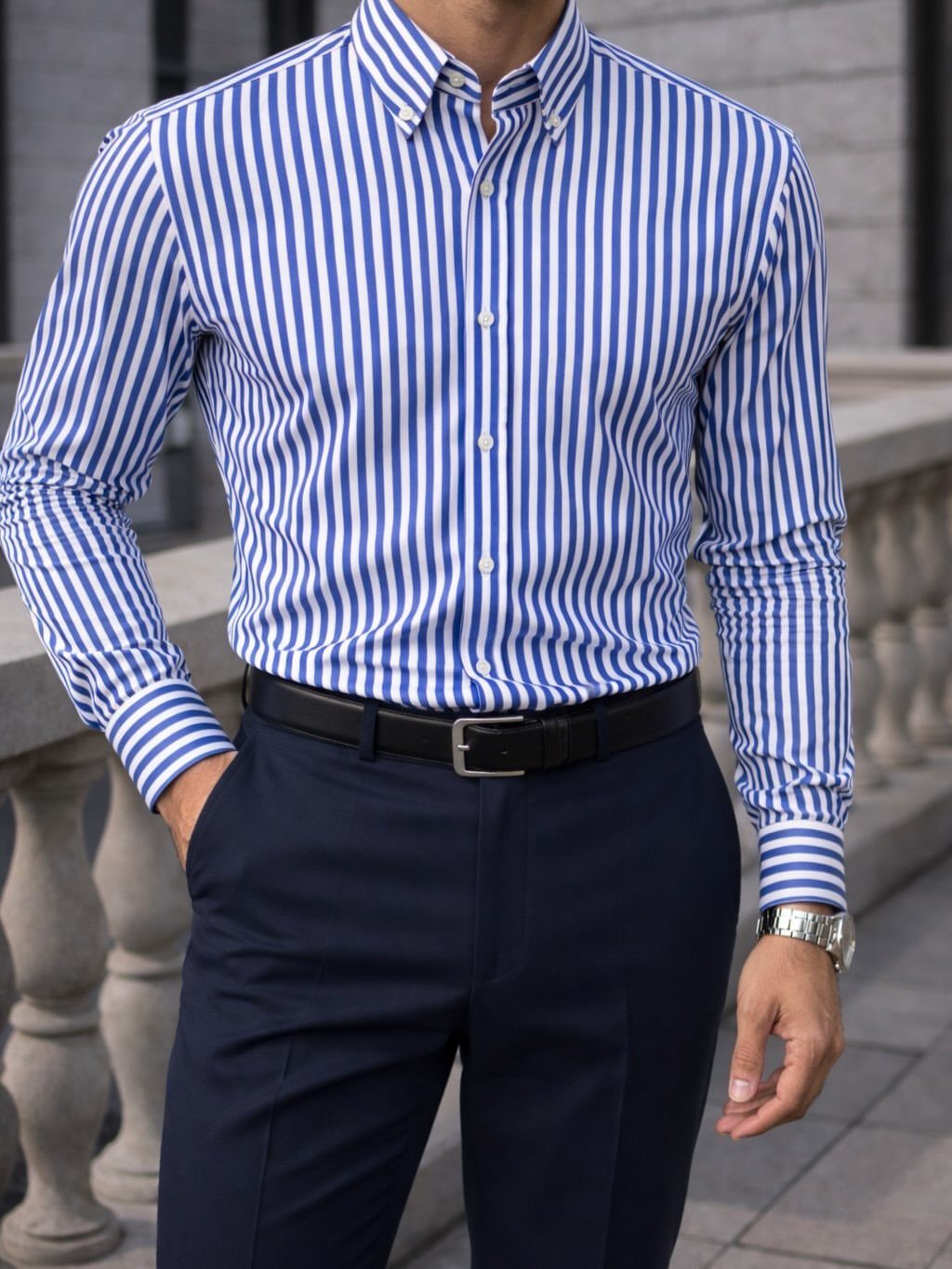 Man wearing a blue striped shirt tucked into navy blue chinos with black belt