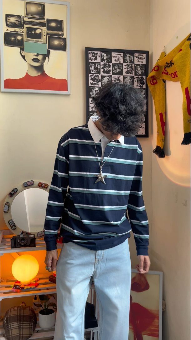 Person wearing a navy and light blue striped shirt with light blue jeans.