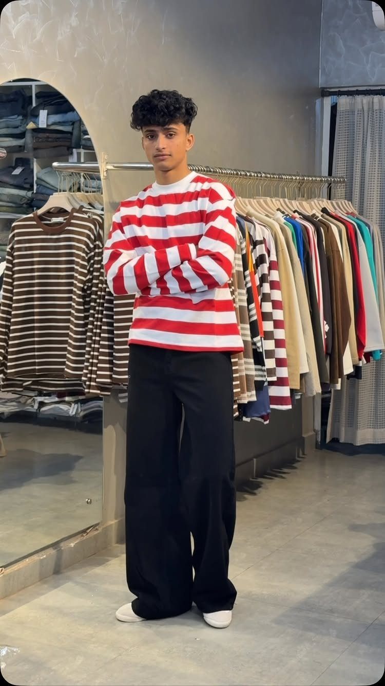 Man wearing red and white striped shirt with wide black trousers in store