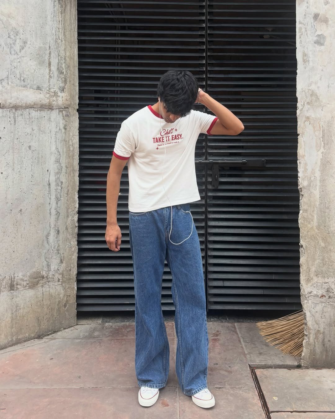 Person wearing relaxed straight blue jeans, white t-shirt, and white sneakers outdoors.