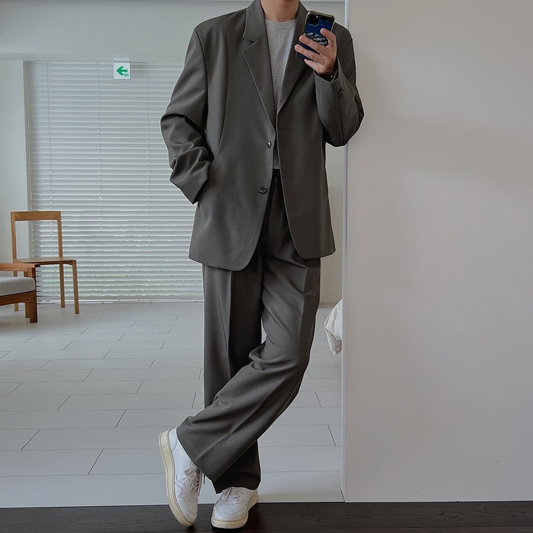 Person wearing a grey oversized blazer and wide-leg trousers with white sneakers.