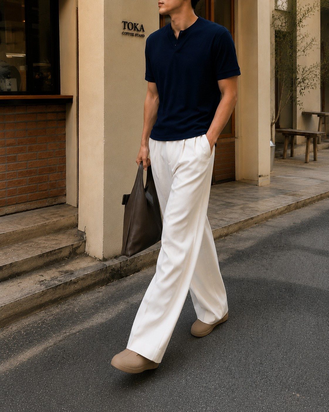 Man in navy shirt and white wide-leg trousers walking on a city street