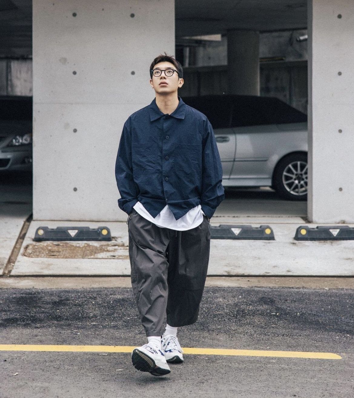 Man in navy shirt and grey wide-leg pants wearing white chunky sneakers.