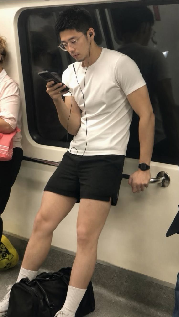 Man in white t-shirt and black athletic shorts standing on a train