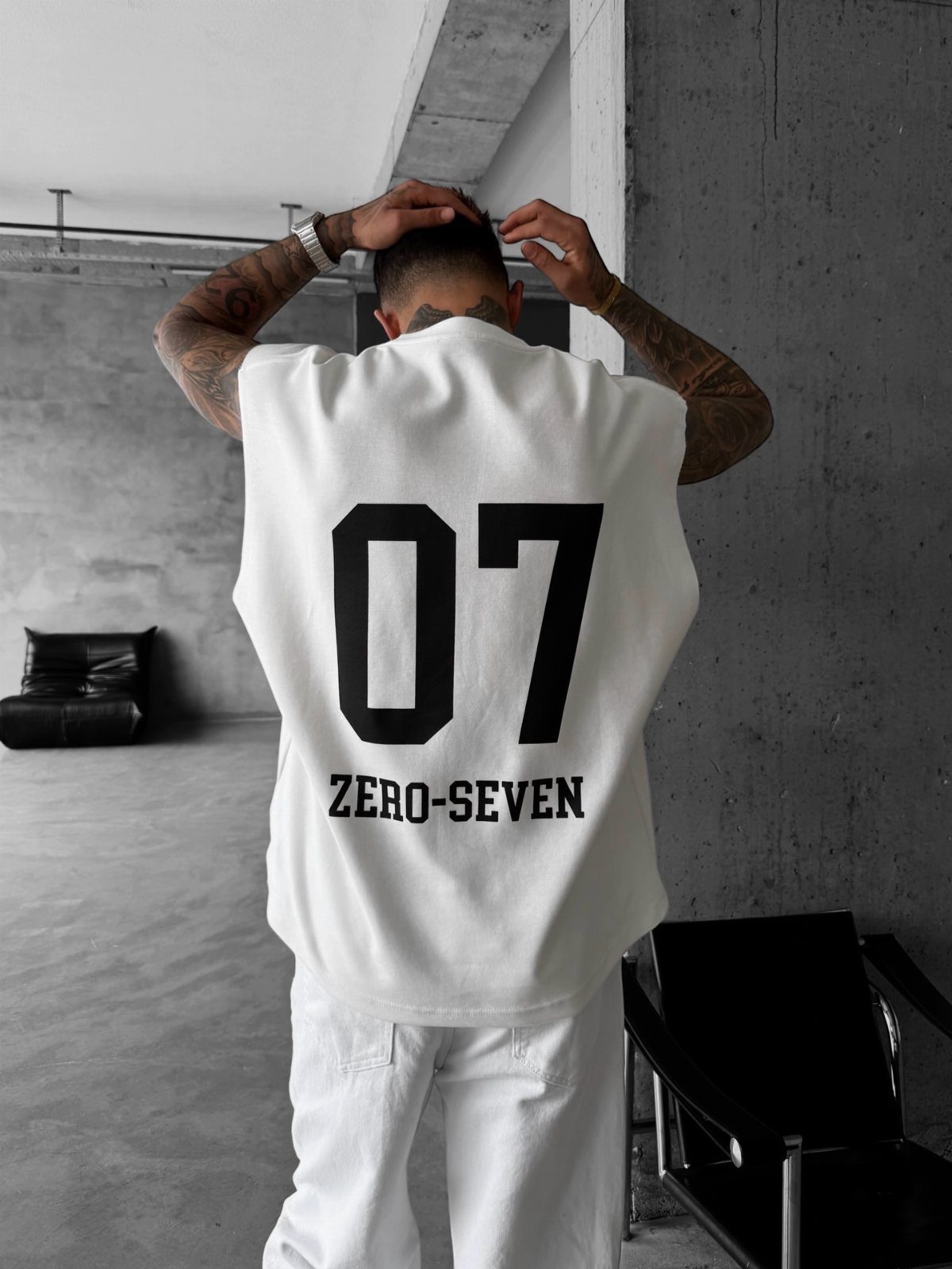 Man from behind wearing white oversized logo t-shirt and matching white jeans.