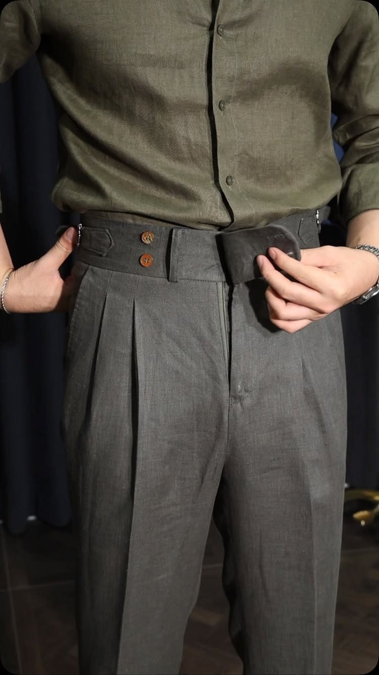Grey pleated linen trousers with a high waist worn with a green shirt.