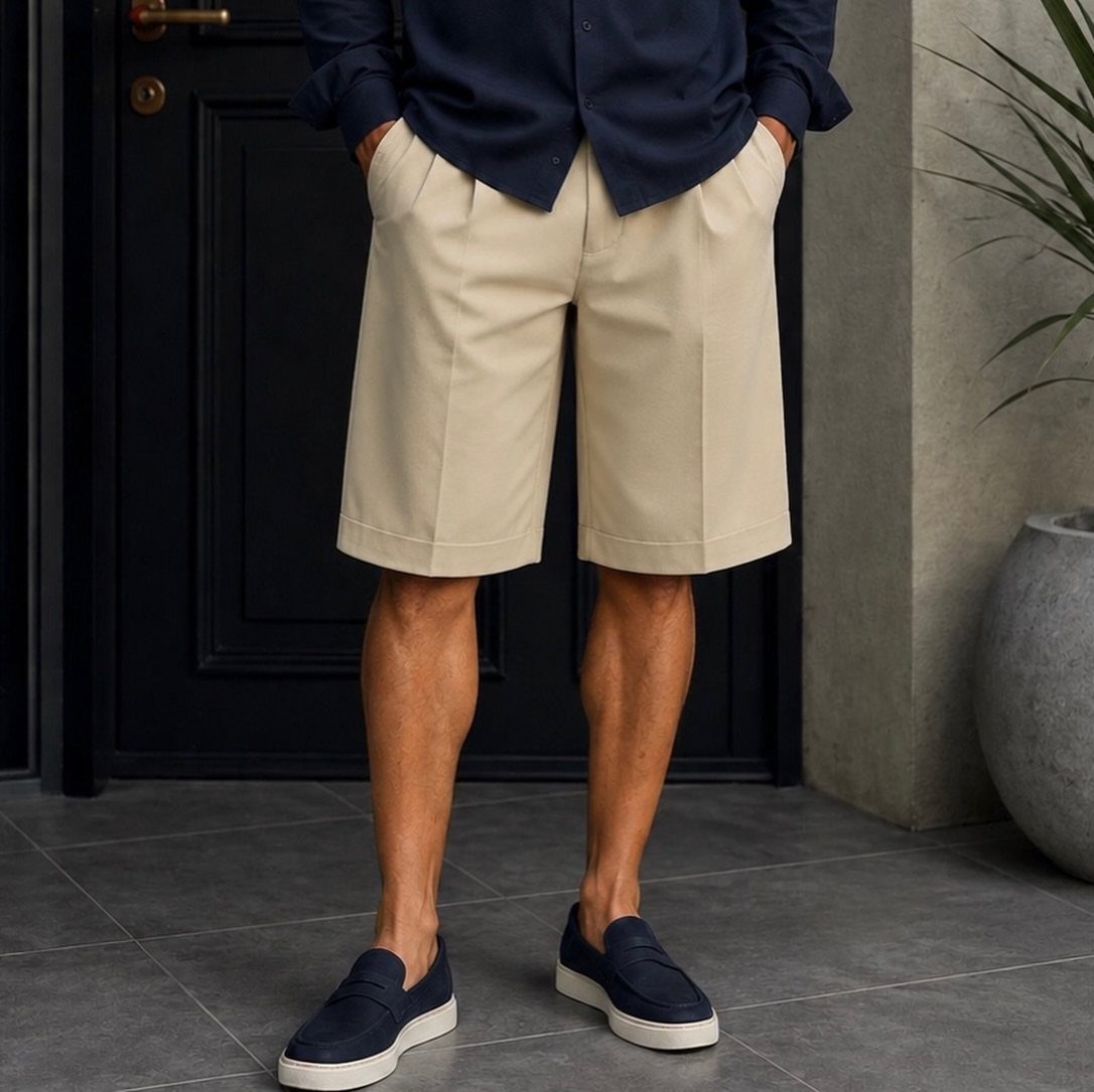 Beige tailored shorts paired with a navy shirt and loafers on a man.