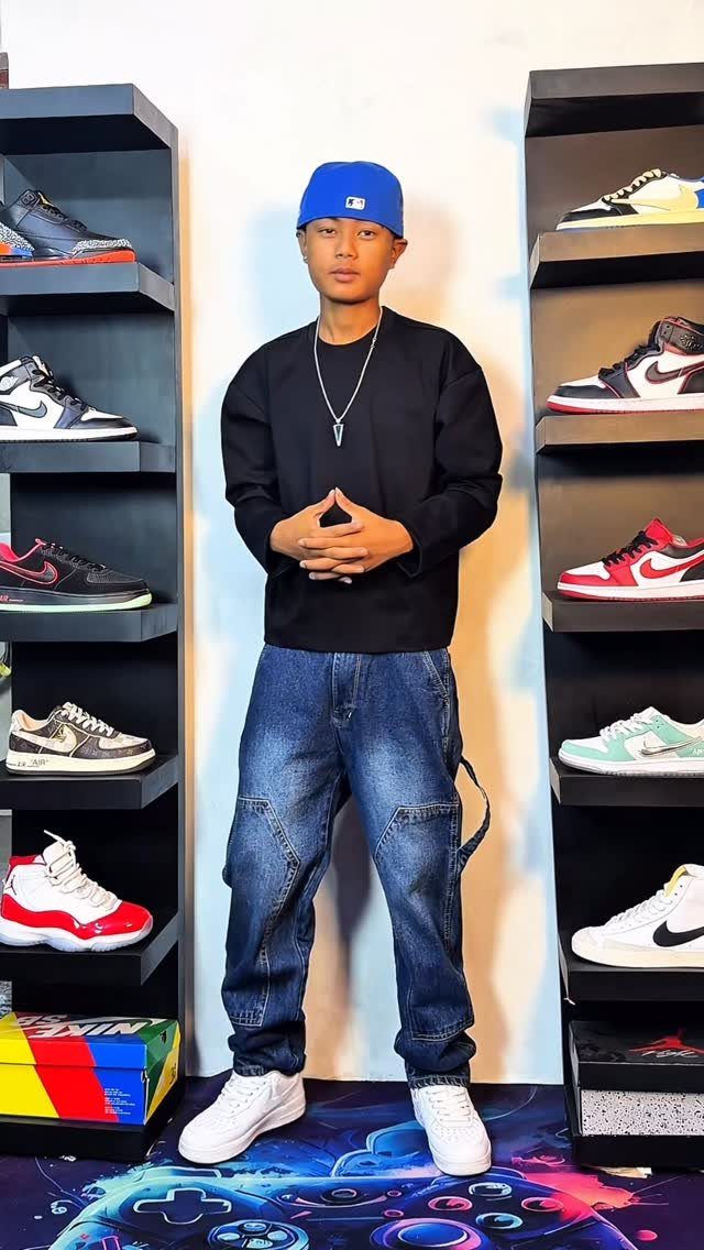 Man wearing blue denim carpenter pants with utility pockets and white sneakers.