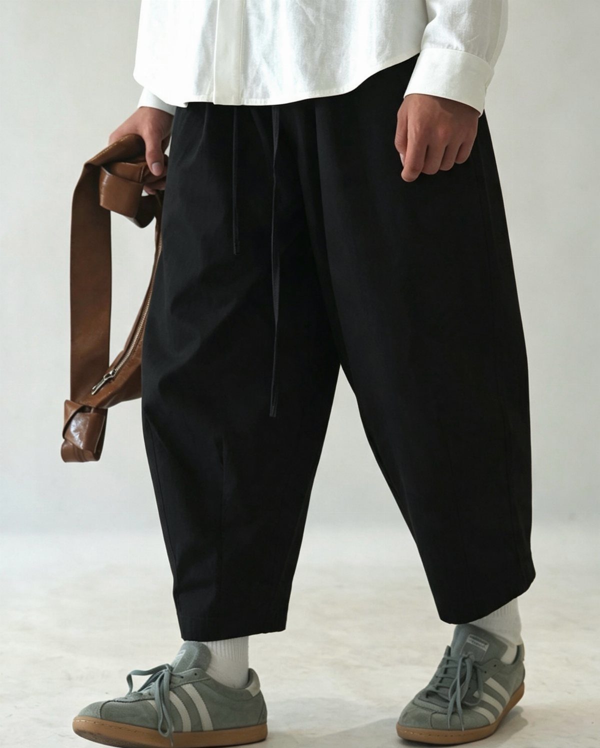 Black cropped pants paired with a white shirt and olive green sneakers.