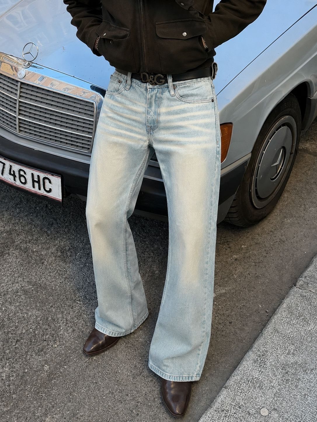 Light-wash bootcut jeans worn by a person standing next to a blue vintage car.