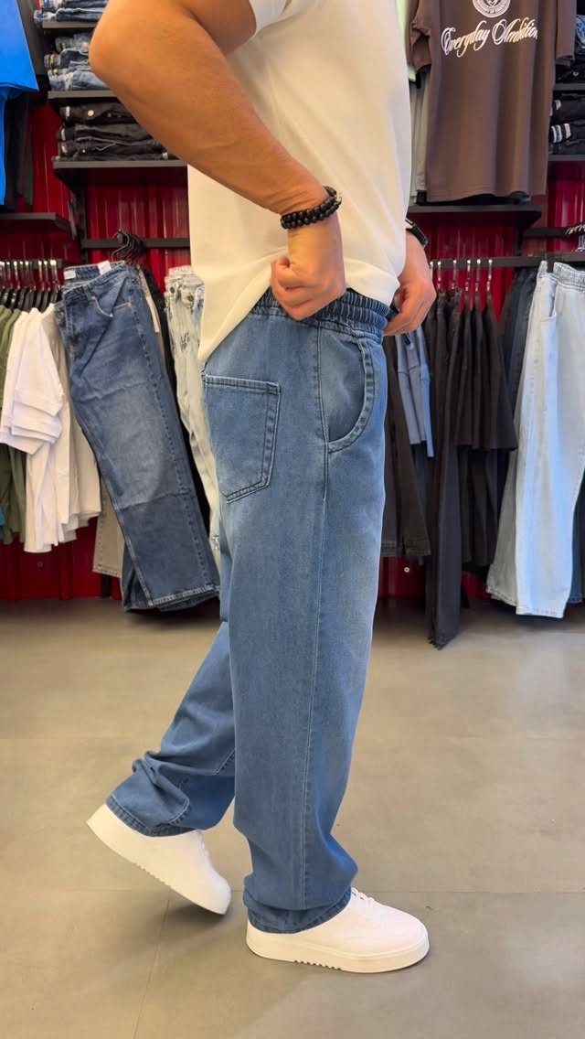 Person wearing light blue jogger jeans with elastic waist and white sneakers.