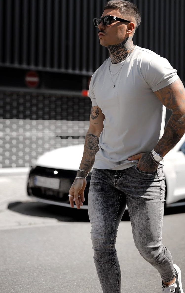 Man wearing tight grey acid-wash skinny jeans and a light grey t-shirt.