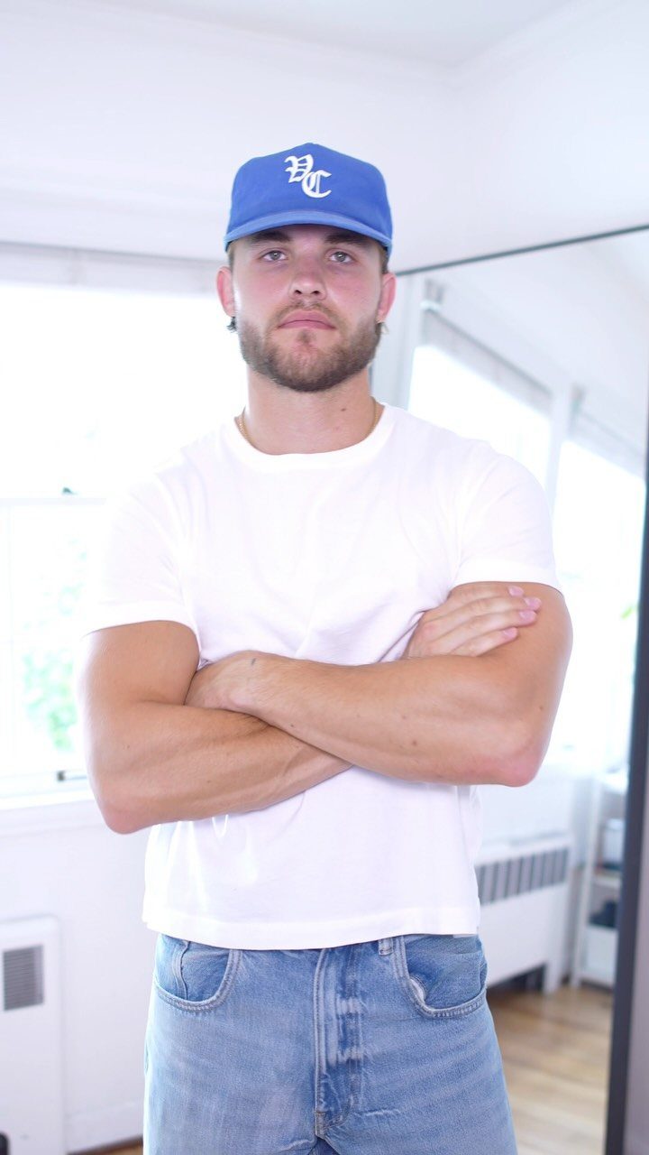 Man wearing a white t-shirt, blue jeans, and a blue baseball cap.