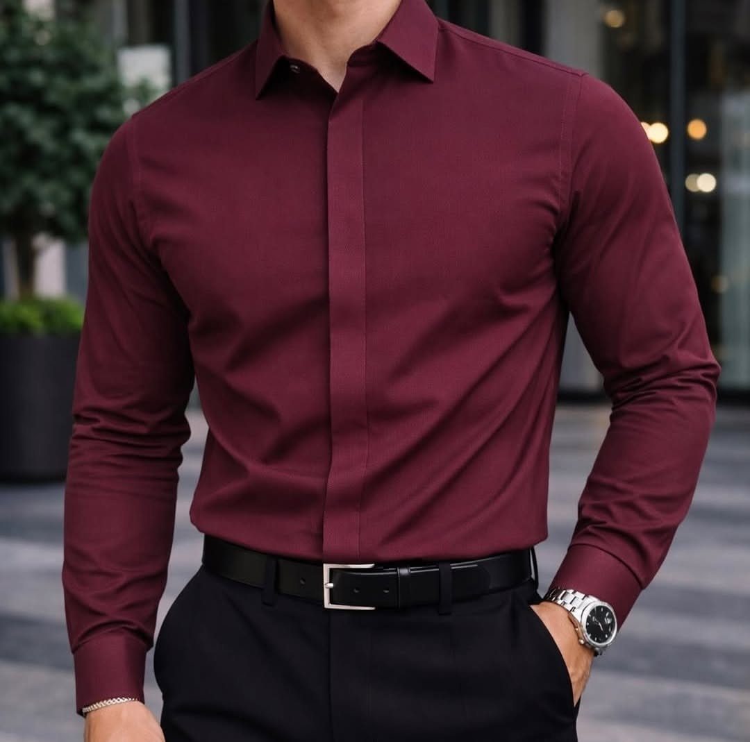Man wearing a slim-fit burgundy dress shirt tucked into black trousers with belt.