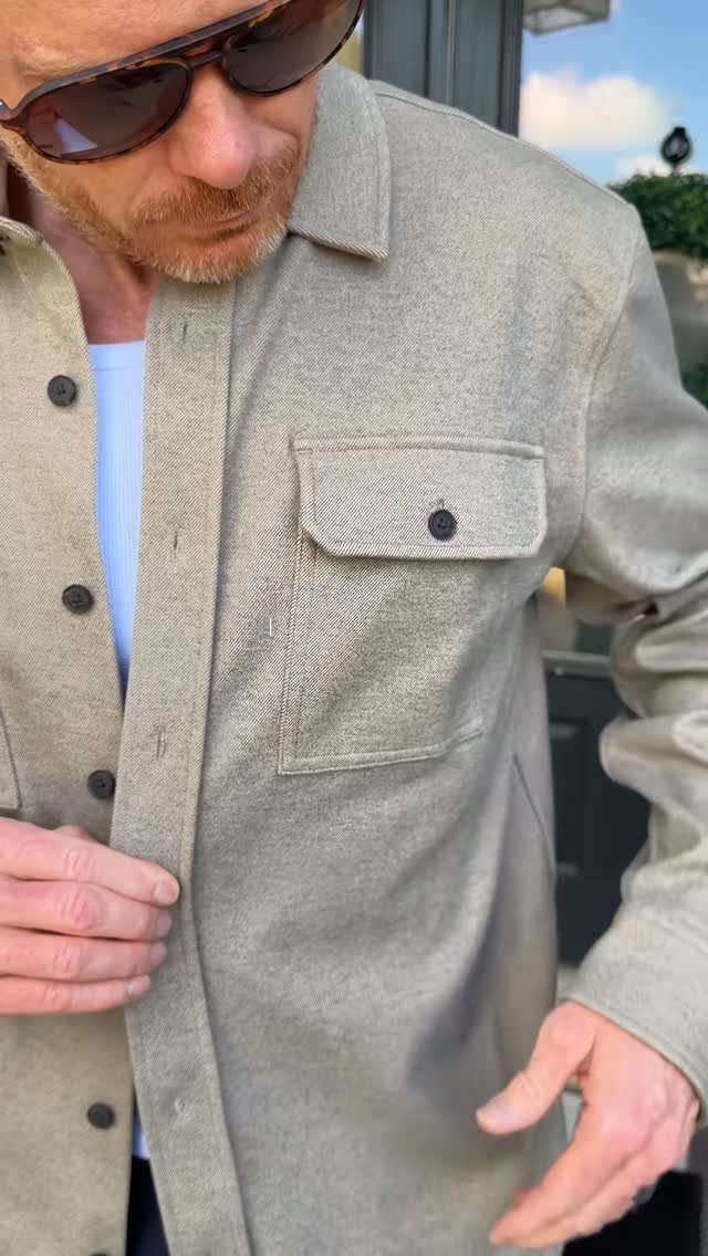 Man wearing a light beige heavy fabric overshirt with a buttoned chest pocket.