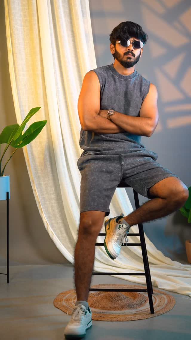 Man wearing a grey sleeveless t-shirt and matching shorts posing in a studio