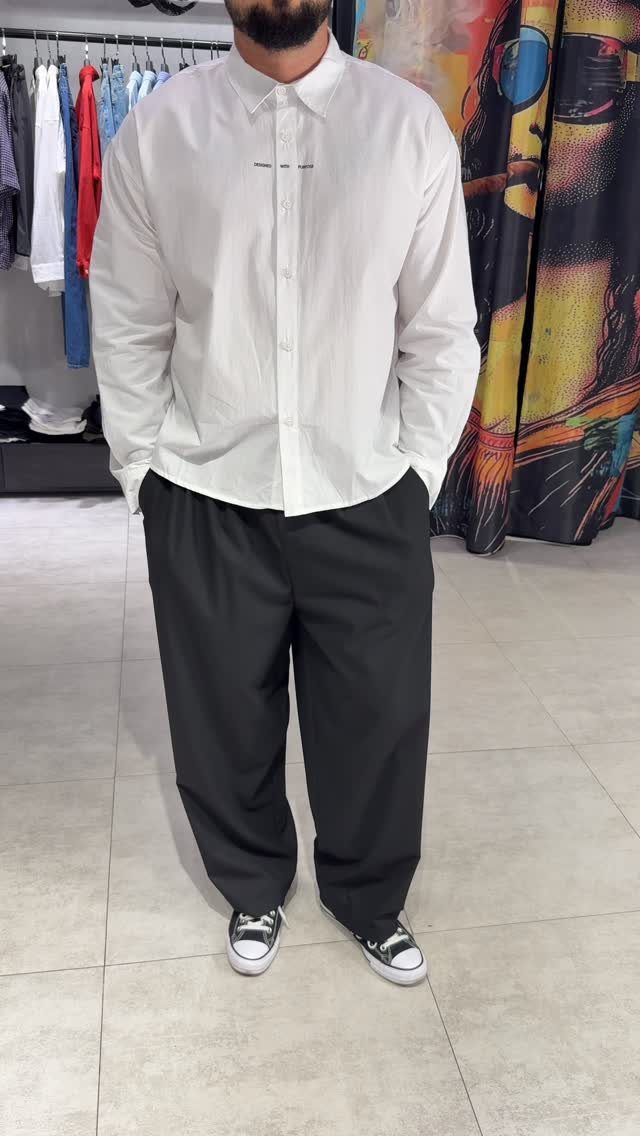 Person wearing a white button-down shirt and black trousers in a clothing store.