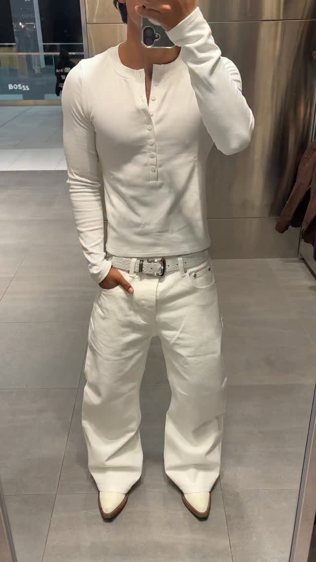Person wearing a white long-sleeve henley shirt and wide-leg white jeans.
