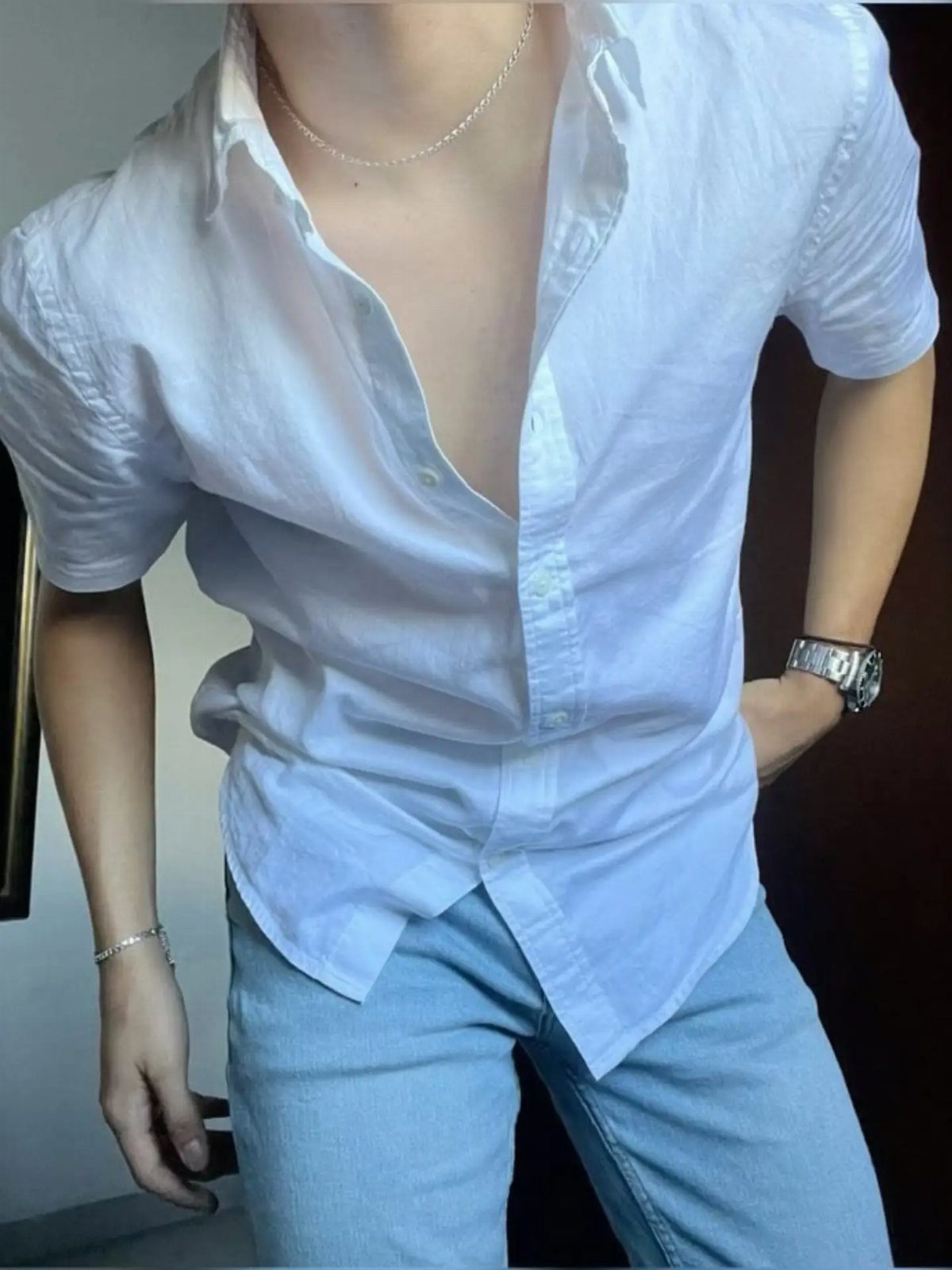 Person wearing a white short-sleeved button-down shirt and light blue denim jeans.